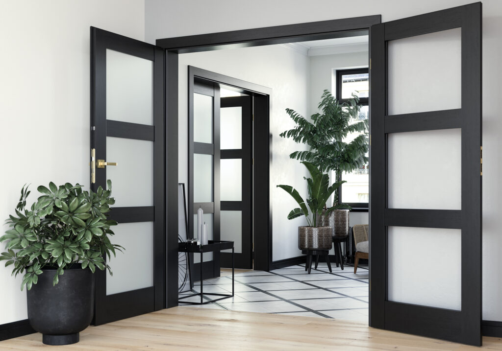 Elegant entryway featuring black-framed frosted glass doors with luxurious gold handles, creating a sophisticated contrast in a modern, airy space with natural elements.